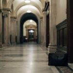 A briefcase waiting alone in an empty marble hallway outside a chamber door — representing lobbying, organized efforts to influence government decisions